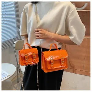 Detail of bright orange jelly Cambridge bags with gold buckles and chain straps
