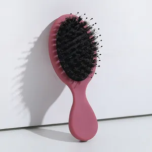 Detalle de un cepillo de pelo rosa con cerdas de jabalí para el peinado y el cuidado del cuero