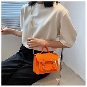 Detail shot of a vibrant orange mini jelly Cambridge bag with a gold chain strap