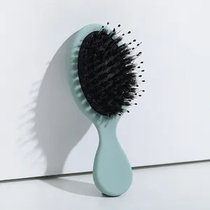 Detalle de cepillo de pelo verde menta con cerdas de jabalí para masaje y peinado