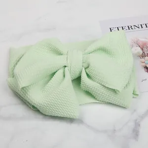Detail view of light green bubble textured fabric child headband with large bow