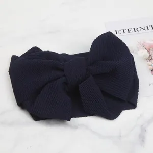 Close-up of a navy blue baby headband made of bubble texture fabric with a large bow detail