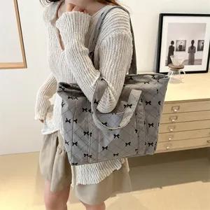 Trendy gray corduroy quilted tote bag featuring delicate black bow patterns for women