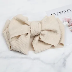 Detailed macro view of cream textured waffle fabric baby headband with large bow