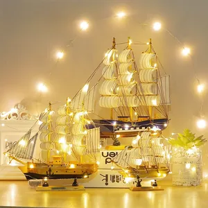Vista dettagliata di tre modellini di navi a vela in legno con calde luci a LED decorative