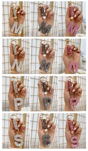 Close-up of rhinestone letter keychains in silver, grey, and pink for bag charms.