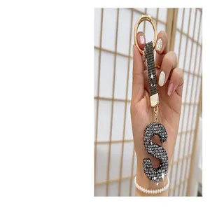 Close-up of a sparkling rhinestone letter S keychain held by hand for bag charms.