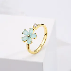 Detail van een 18K vergulde ring met een blauwe bloem en een schitterende zirkoon