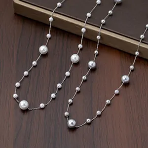 Detailed view of elegant long pearl station necklace draped on a dark wooden surface