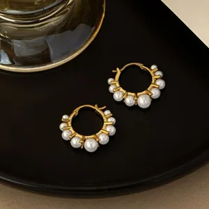 Close-up view of elegant vintage gold hoop earrings adorned with lustrous white pearls.