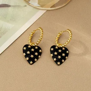 Detailed macro view of vintage heart earrings featuring black enamel and gold stars pattern.