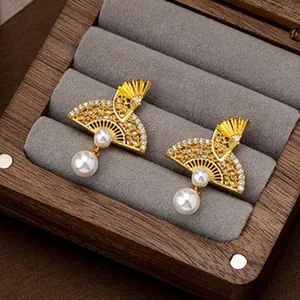 Detailed view of vintage gold fan-shaped earrings with pearls in a jewelry box