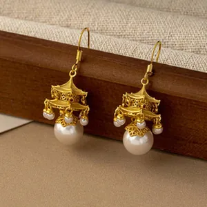 Macro view of vintage gold pavilion style earrings decorated with elegant hanging white pearls.