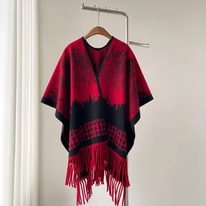 Detail view of red and black houndstooth patterned knit poncho with fringed hem.