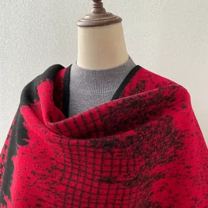 Detailed view of a thick red and black houndstooth pattern winter shawl cape on a mannequin.
