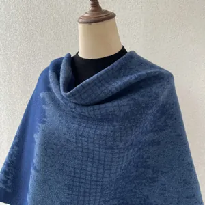 Detailed close-up of a blue houndstooth patterned shawl poncho draped on a professional mannequin