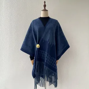 Close-up view of a dark blue houndstooth shawl featuring elegant long fringes and gold clasp