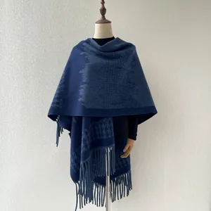 Detailed view of navy blue houndstooth poncho on a mannequin with fringe trim