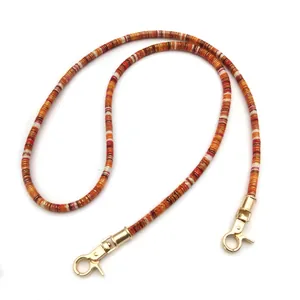 Detailed view of a retro colorful woven rope bag strap with gold metal lobster clasps
