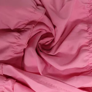 Vue macro d'un tissu rose doux avec des coutures détaillées et des plis pour ensemble