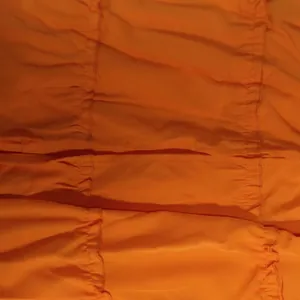 Détail macro de la texture du tissu plissé orange vif pour ensemble robe d'été