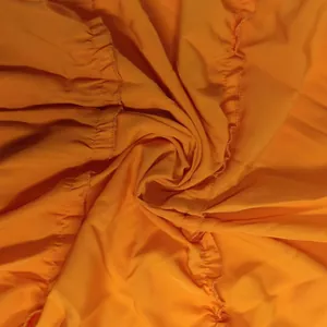 Vue détaillée d'un tissu plissé orange vif montrant des coutures et une texture complexes
