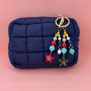 Detail showing a navy blue quilted cosmetic bag with a colorful beaded star keychain charm
