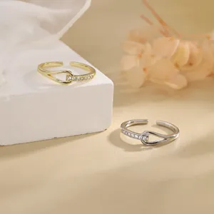 Detail of minimalist adjustable open rings with interlocking zircon knot design in gold and silver.