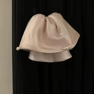 Close-up of elegant champagne satin headband featuring voluminous pleats and pearl accents.