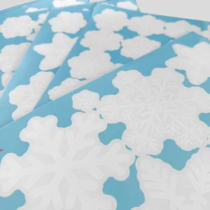 Gros plan de plusieurs feuilles de stickers statiques flocons de neige sur papier bleu