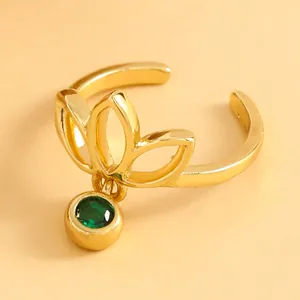 Close-up of a golden lotus openwork toe ring featuring a dangling green gemstone