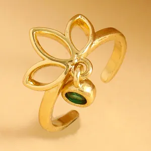 Close-up detail of a golden hollow geometric metal toe ring featuring a green stone charm