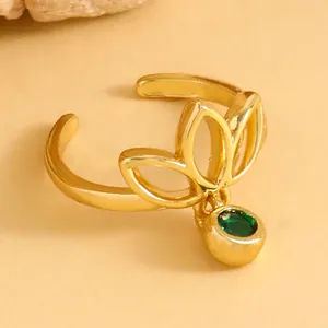 Macro view of gold hollow lotus toe ring featuring a vibrant dangling green gemstone
