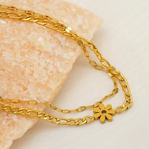 Detailed macro view of a double-layered gold Figaro chain bracelet with flower charm