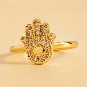 Macro view of gold Hamsa hand ring featuring micro-paved cubic zirconia and evil eye