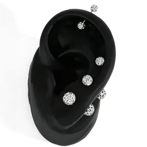 Macro detail of silver Shamballa crystal ball stud earrings displayed on a black ear model