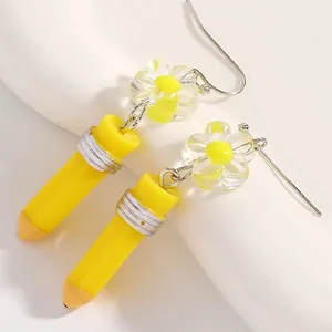 Whimsical yellow pencil dangle earrings featuring a clear resin flower charm detail