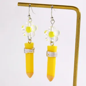Creative yellow pencil earrings with clear flower charms on a gold jewelry stand