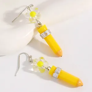 Detailed close-up of creative yellow pencil drop earrings with clear flower charms