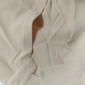 Detailed macro view showing the high-quality stitching and beige fabric texture of the shirt