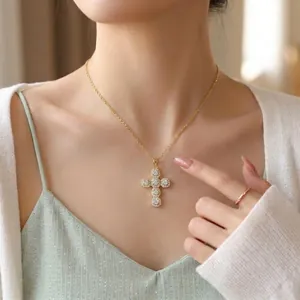 Collier élégant à pendentif croix dorée avec cristaux étincelants porté par un mannequin.