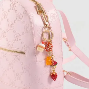 Detailopname van een tashanger met cupcake-, pretzel- en beermotieven op een roze rugzak.