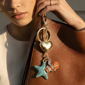 Close-up of ocean-themed bag charm with starfish and clownfish on a brown leather bag