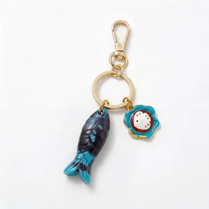 Detailed view of marine series fish and flower charms on a gold-tone keychain.