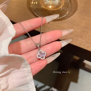 Silver flower pendant necklace with central clear gem shown in close-up detail view