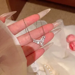 Detail of silver titanium steel necklace with V-shaped crystal pendant and pearl.