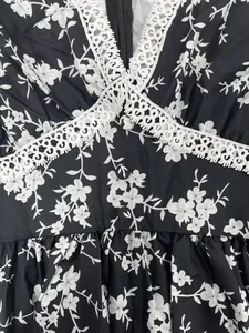 Gros plan d'une robe fleurie col en V avec dentelle blanche et détails de boutons
