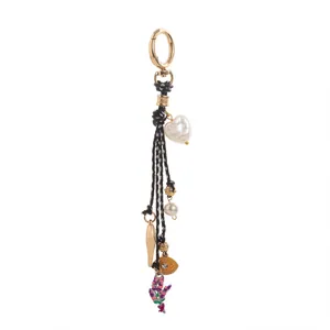 Détail d'un porte-clés multi-breloques avec perle en cœur et pendentif œil doré.