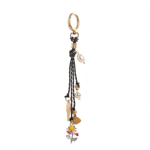 Détail d'un pendentif bohème avec cordon noir, perles, œil et breloques de fleurs