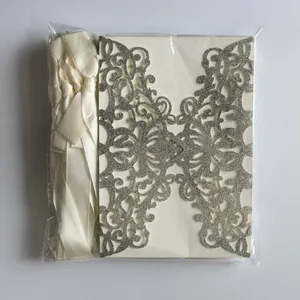 Macro view of silver glitter laser-cut wedding invitation card and cream ribbon